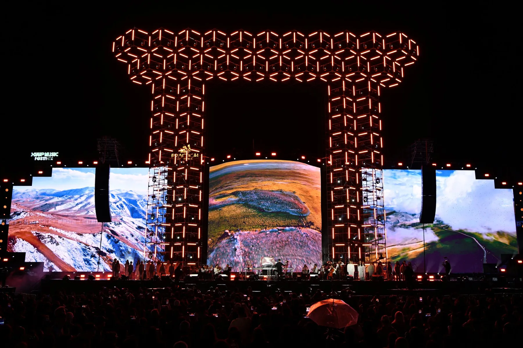 The Kharkhorum gate lit in orange LED over a crowd